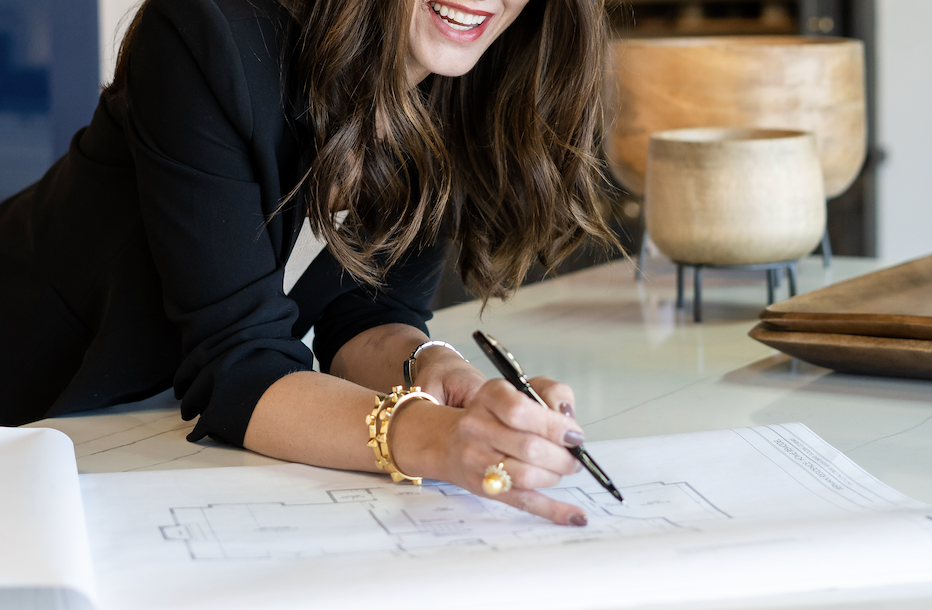 A smiling woman looking at a blueprint
